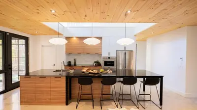 a kitchen with a black island with bar stools at Le Bois Debout - Lake & Trails in Eastman