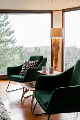 a living room with green chairs and a table at L'Orford VIEW POOL TENNIS SPA in Orford