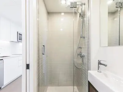 a white bathroom with a shower and a sink at Sky Bridge Spectacular in Montréal