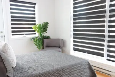 a bedroom with a bed and a chair and windows at Luxury Artist Condo In Montreal in Montréal