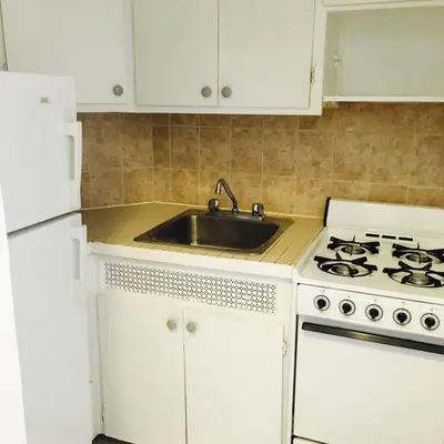 a white kitchen with a sink and a stove at Stylish Montreal Apartment Comfortable Stay in the Golden Square Mile in Montréal