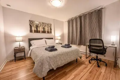 a bedroom with a bed and a desk and a chair at Modern 3BR 4beds apartment AC WiFi Free Parking in Laval
