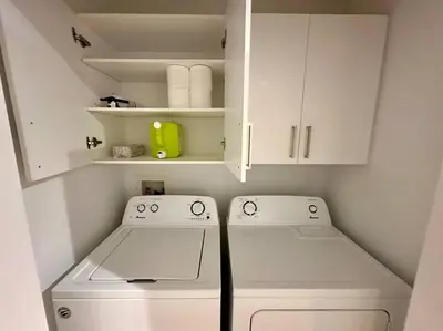 a small kitchen with white cabinets and a washer at Modern 3BR 4beds apartment AC WiFi Free Parking in Laval