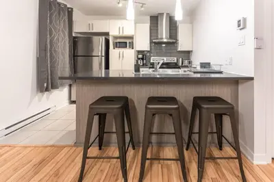 a kitchen with two stools at a kitchen counter at Modern 3BR 4beds apartment AC WiFi Free Parking in Laval
