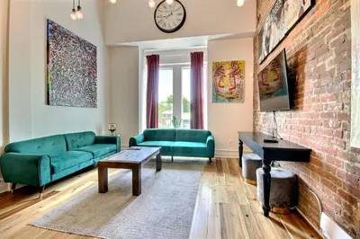 a living room with green furniture and a brick wall at Galeria St Denis in Prime Montreal in Montréal