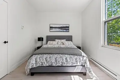 a white bedroom with a bed and a window at Appartement haut de gamme NDG in Montréal