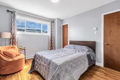 a bedroom with a bed and a chair and a window at Cozy 3 Bedrooms Montreal in Montréal