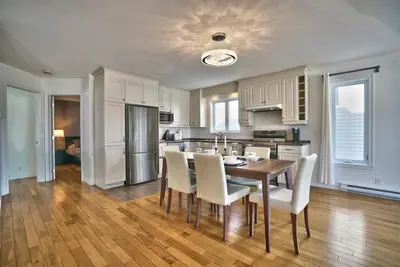 a kitchen with a wooden table and white cabinets at Dynamite 2-Bedroom House, Garage, Sleeps 6 in Sherbrooke