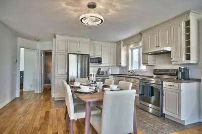 a kitchen with a wooden table and white cabinets at Dynamite 2-Bedroom House, Garage, Sleeps 6 in Sherbrooke