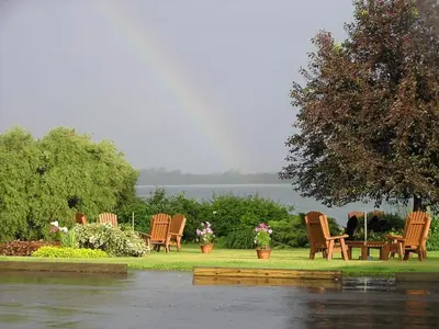 a group of chairs sitting on the grass near the water at Hotel Oasis Lac St-Louis in Salaberry de Valleyfield