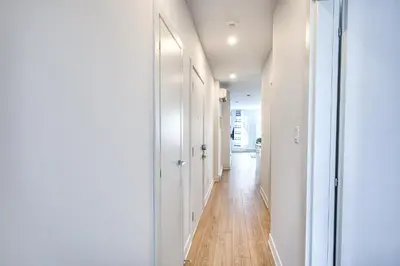 a hallway with white walls and a wooden floor at Beautiful & New! Renovated for your Style Comfort in Montréal