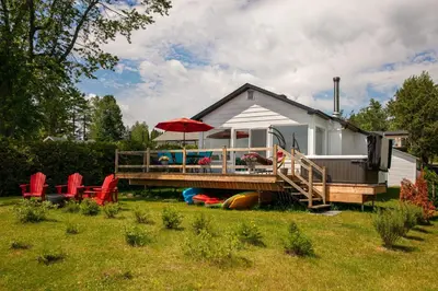 a small house with a deck and an umbrella at La Cozy O-Lac Magog in Sherbrooke