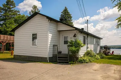 a small white house on the side of a street at La Cozy O-Lac Magog in Sherbrooke