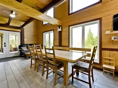 a dining room with a wooden table and chairs at Spa Nature Estrie in Saint-Herménégilde