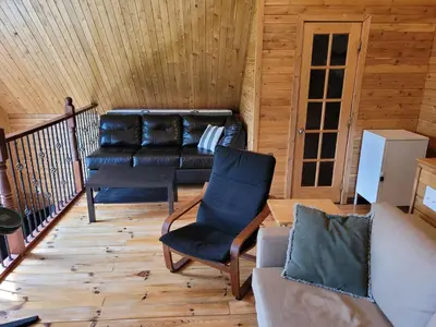 a living room with a leather couch and a chair at Spa Nature Estrie in Saint-Herménégilde