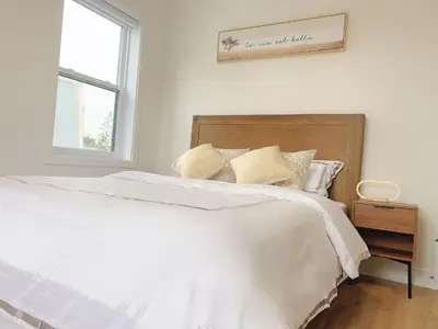 a bedroom with a bed with white sheets and a window at 10 minutes to DT with Free parking in Longueuil