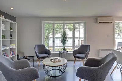 a living room with chairs and a table and a window at La vie O-Lac Magog in Sherbrooke