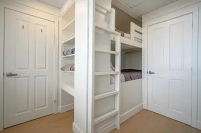 a walk in closet with white doors and a bed at La vie O-Lac Magog in Sherbrooke