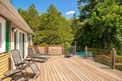 a wooden deck with chairs and a table at La vie O-Lac Magog in Sherbrooke