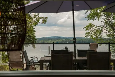 a table and chairs with a view of a lake at La Vue O-Lac Magog in Sherbrooke