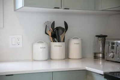 three white containers on a kitchen counter with utensils at La Vue O-Lac Magog in Sherbrooke