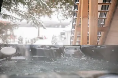 a hot tub with water in it next to a house at La Vue O-Lac Magog in Sherbrooke