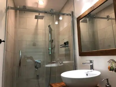 a bathroom with a sink and a shower with a mirror at Rooms in peaceful nature settings in Sutton