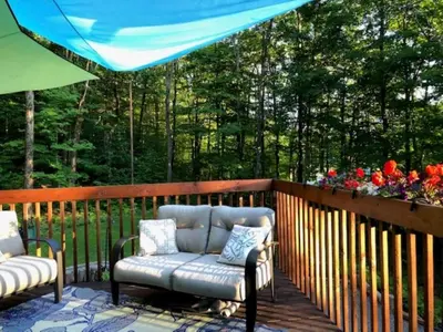 a patio with two chairs and a blue umbrella at Rooms in peaceful nature settings in Sutton