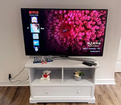 a flat screen tv on a white tv stand at Spacious basement apartment in Montréal