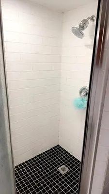 a bathroom with a shower with a black tile floor at Spacious basement apartment in Montréal