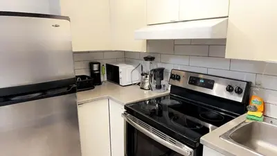 a kitchen with white cabinets and a stove top oven at Spacious basement apartment in Montréal