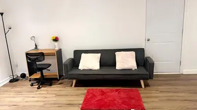 a living room with a black couch and a desk at Spacious basement apartment in Montréal