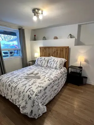 a bedroom with a bed with a white comforter and a window at La Suite Centre-ville Saint-Georges in Saint-Georges