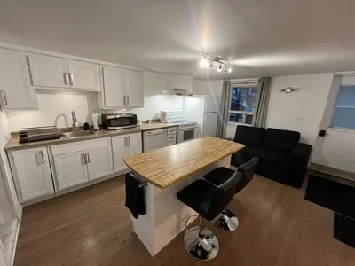 a kitchen with white cabinets and a wooden counter top at La Suite Centre-ville Saint-Georges in Saint-Georges