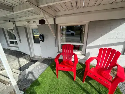 two red chairs sitting on the front porch of a house at La Suite Centre-ville Saint-Georges in Saint-Georges