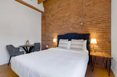 a bedroom with a white bed and a brick wall at The Little Prince Rooms-Old Montreal in Montréal