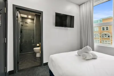 a bedroom with a bed and a bathroom with a shower at Lift Hotel in Montréal
