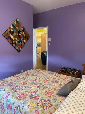 a bedroom with a bed and a purple wall at Auberge Le Wagon in Wotton