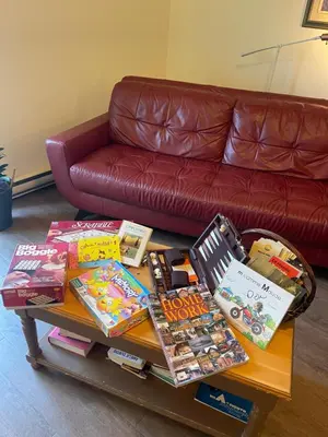 a living room with a couch and a table with books at Auberge Le Wagon in Wotton