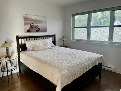a bedroom with a large bed with two windows at Luna's Room in Longueuil