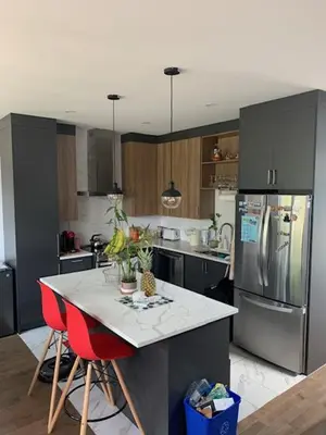 a kitchen with a refrigerator and a table with red chairs at Luna's Room in Longueuil