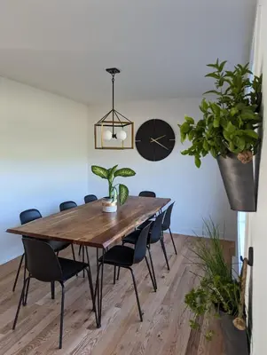 a dining room table with chairs and a clock on the wall at 4 bedrooms New House in Farnham