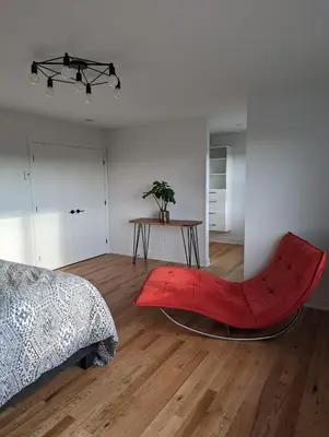 a living room with a red chair and a table at 4 bedrooms New House in Farnham