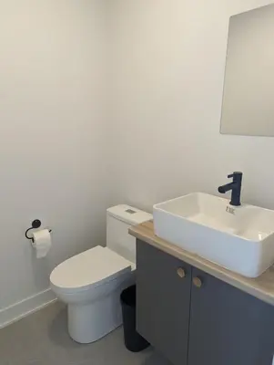 a bathroom with a white toilet and a sink at 4 bedrooms New House in Farnham