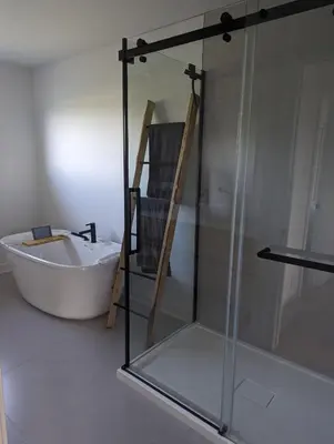 a bathroom with a tub and a glass shower at 4 bedrooms New House in Farnham