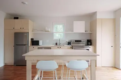 a kitchen with a table and three white chairs at Chalet 2 OST Shefford in Shefford