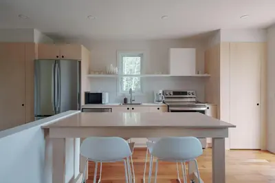 a kitchen with a large island with four white chairs at Chalet 6 OST Shefford in Shefford