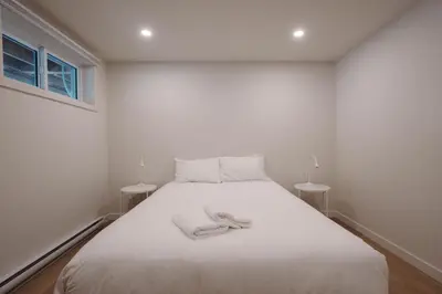 a white bedroom with a bed with two tables at Chalet 3 OST Shefford in Shefford