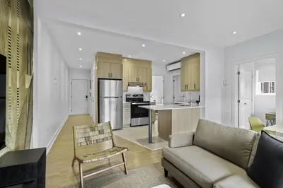 a living room with a couch and a kitchen at Renovated 2-Bedroom Haven by Jean Talon Market in Montréal