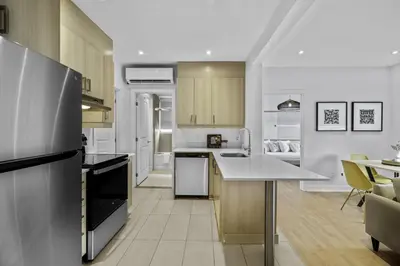 a kitchen with a refrigerator and a table in it at Renovated 2-Bedroom Haven by Jean Talon Market in Montréal
